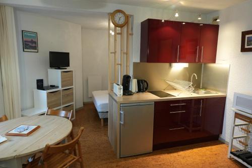 une cuisine avec des placards rouges et une table ainsi qu'une chambre dans l'établissement appartement 4 personnes, ascenseur, balcon, 100 m du télécabine, à Cauterets