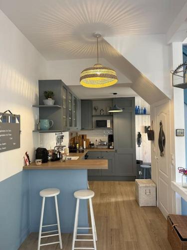 - une cuisine avec un comptoir et deux tabourets dans l'établissement Charmante maison Cabourgeaise, à Cabourg