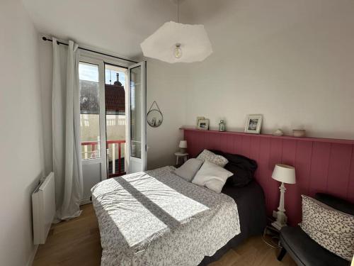 une chambre avec un lit et un mur rose dans l'établissement Charmante maison Cabourgeaise, à Cabourg