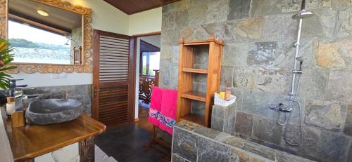 a stone bathroom with a shower and a sink at Villa Ta'u Here in Arue