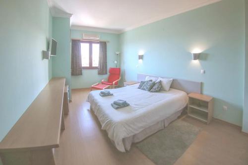 Un dormitorio con una cama y una silla roja. en Ericeira Beach Tour, en Ericeira