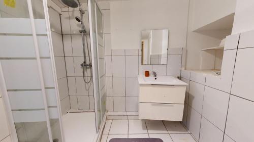 une salle de bain blanche avec une douche et un lavabo dans l'établissement Le Nid Caché Mulhouse, à Mulhouse