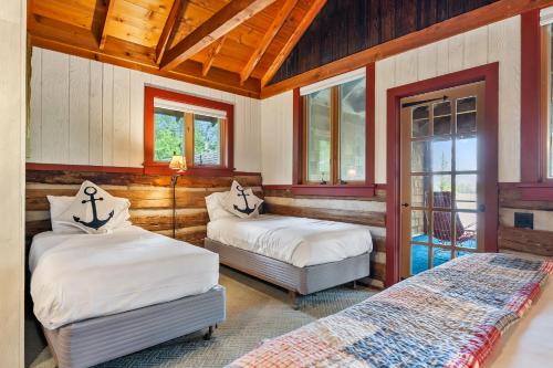 two beds in a room with wooden ceilings and windows at Log Cabin on Kangaroo Lake by Simple Life Rentals in Baileys Harbor
