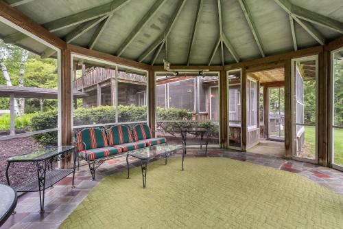 a screened in porch with chairs and tables and windows at Log Cabin on Kangaroo Lake by Simple Life Rentals in Baileys Harbor