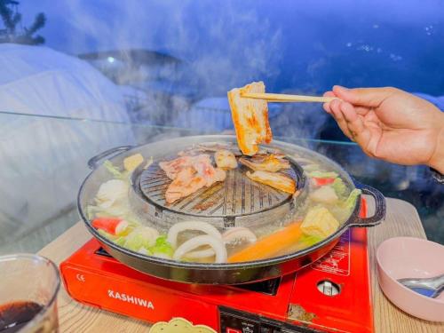 a person is cooking food on a grill at ไร่มีนา ม่อนแจ่ม in Chiang Mai