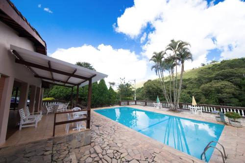 a pool at a resort with chairs and trees at Pousada Ypê das Montanhas in Monte Alegre do Sul