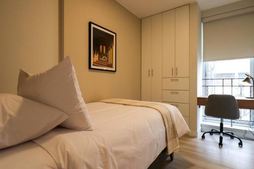 リマにあるCharming 2BR with Balcony in Mirafloresのベッドと机と窓のある寝室