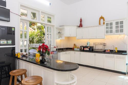 a kitchen with white cabinets and a black counter top at Minh Phước Villa 12 Kim Ngân in Vung Tau