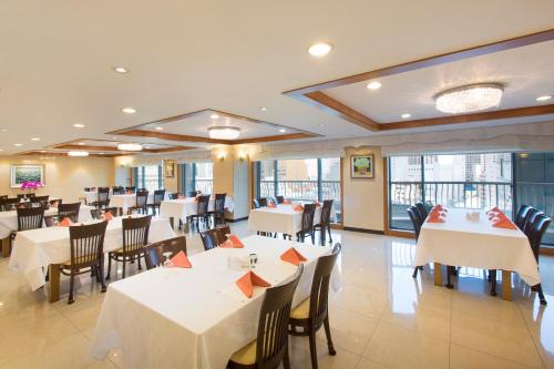 a dining room with white tables and chairs at Libero Hotel in Busan