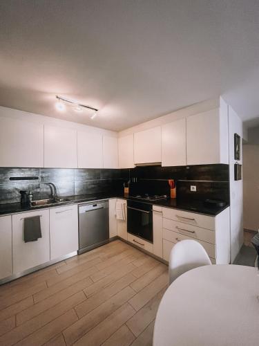 a kitchen with white cabinets and a wooden floor at Casinha Praia Azul in Costa de Lavos