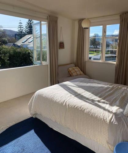 a bedroom with a bed and a large window at Sunny 3 Bedroom with garden close to hospital in Lower Hutt