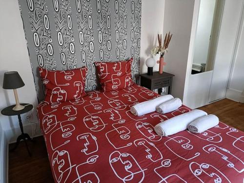 - un lit avec une couette et des oreillers rouges dans l'établissement Agréable studio - WiFi, à Dijon