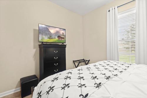 a bedroom with a bed and a tv on a dresser at Petfriendlymid-term Stays2king Beds&desk in Lake Charles