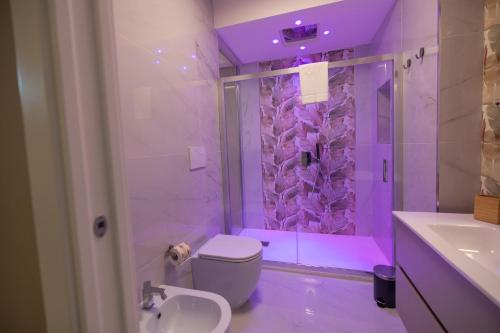a bathroom with a toilet and a shower with purple lighting at Luxury Rooms in Somma Vesuviana