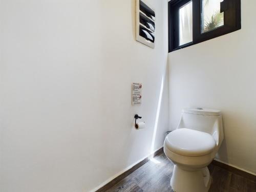 a bathroom with a white toilet and a window at Casa Xaman in Tulum - TH 5 in Tulum