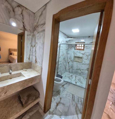 a bathroom with a shower and a sink and a toilet at Jardim Do Eden Piri in Pirenópolis