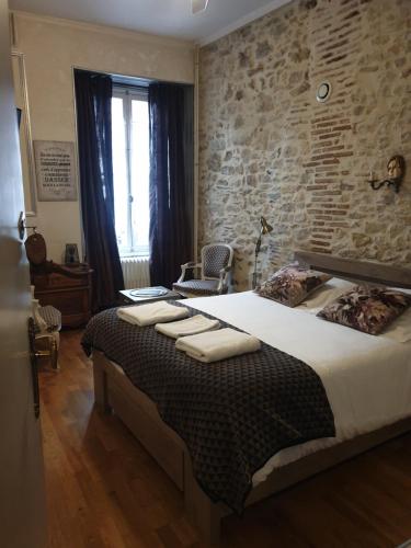 une chambre avec un grand lit et un mur de briques dans l'établissement L'écu, à Saint-Amand-Montrond