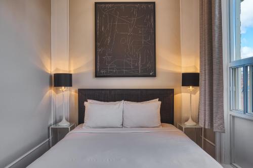 a bedroom with a bed with two lamps and a picture on the wall at The Windsor Hotel by Hoco Hotels Collection in Stratford