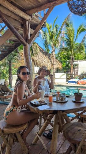 a man and woman sitting at a table in front of a pool at Nuevo NAYAL in Las Peñitas