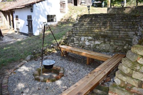 a park bench and a fire pit with a bucket at A kis parasztház in Kékesd