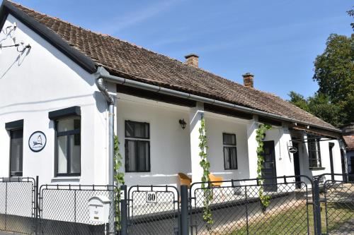 a white house with a fence in front of it at A kis parasztház in Kékesd