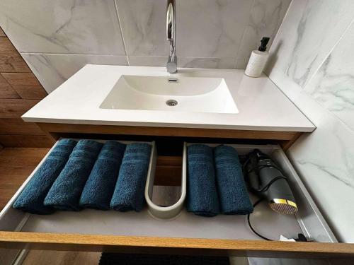 a sink and some blue towels in a drawer under a sink at La Résidence du moulin 2 E pour 6 Personnes in Boussu