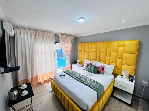 a bedroom with a large bed with a yellow headboard at The greenary guest house and restaurant in Thohoyandou