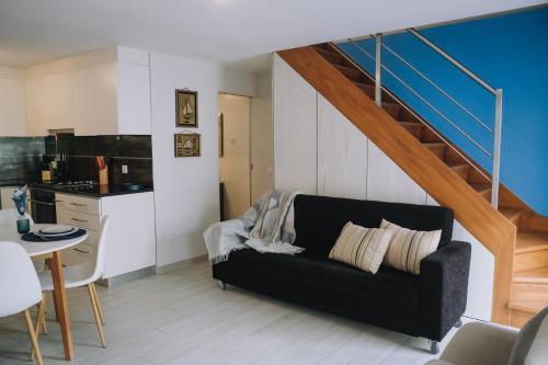 Una sala de estar con un sofá negro y una escalera. en Casinha Praia Azul, en Costa de Lavos