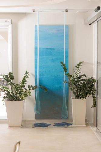 a room with two potted plants in front of a painting at Iria Beach Art Hotel in Agia Anna Naxos