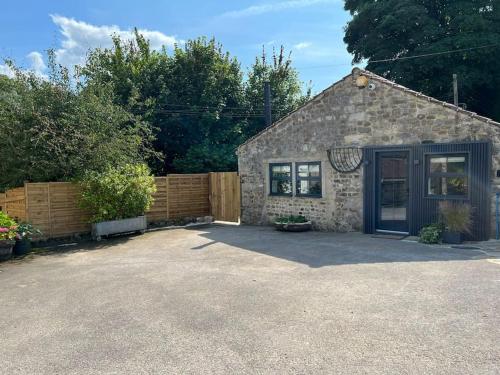 a small stone house with a fence in front of it at Richmond Hill Cottage Markington in Ingerthorpe