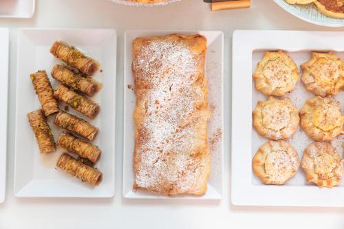a table with three white plates with sandwiches and biscuits at Iria Beach Art Hotel in Agia Anna Naxos
