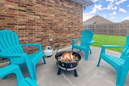 three blue chairs and a fire pit on a patio at Tailored For Work Groups At Thibs Crib in Lake Charles