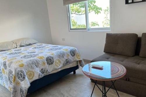 a bedroom with a bed and a couch and a table at Casa Cumbres Tulipanes Descanso Americano in Chiconcuac