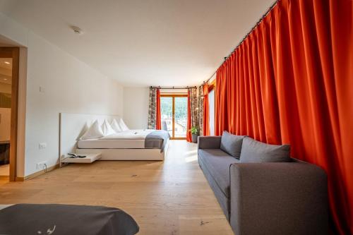 a bedroom with red curtains and a bed and a couch at Hotel Piz St. Moritz in St. Moritz