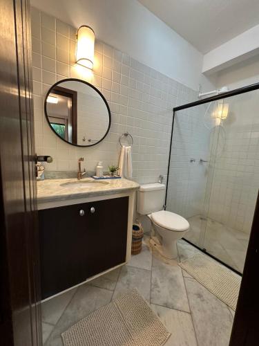 a bathroom with a toilet and a sink and a mirror at Casa Mar Arraial d'Ajuda in Arraial d'Ajuda