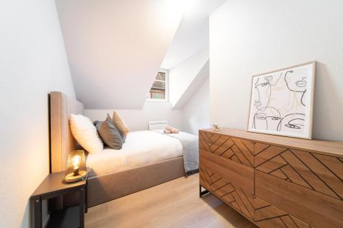 - une chambre avec un lit et une commode avec une télévision dans l'établissement Le Grand Lion Colmar Centre Parking Gratuit, à Colmar