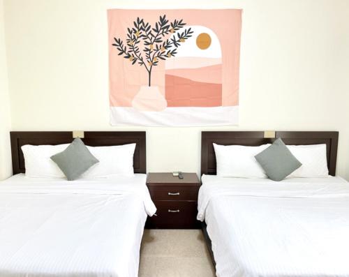 2 Betten mit weißer Bettwäsche und ein Gemälde an der Wand in der Unterkunft 花蓮密絲朵包棟民宿 4-14人 l 近花蓮火車站 l 電動麻將桌 in Hualien