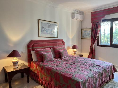 a bedroom with a red bed with two tables and two lamps at Villa familiale Achakkar 2 in Tangier