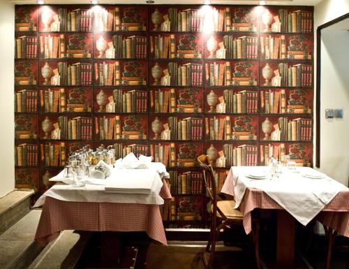 a restaurant with two tables in front of a wall of books at Alkistis Hotel in Portari&aacute;