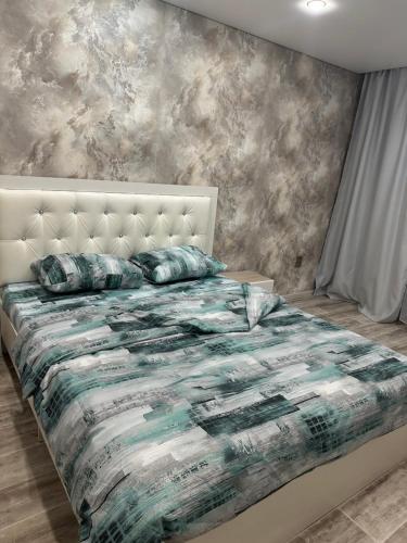 a bedroom with a bed with a comforter and pillows at Двухкомнатная уютная квартира in Ekibastuz