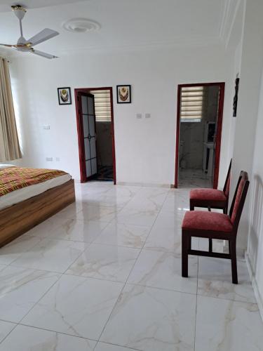 a bedroom with a bed and a pair of chairs at Pool House Retreat in Accra in Accra