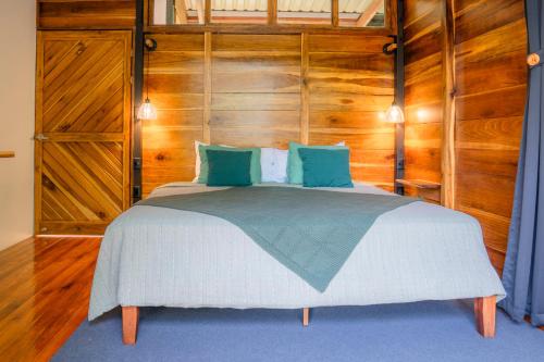 a bedroom with a large bed with wooden walls at Arenal Getaway in Fortuna