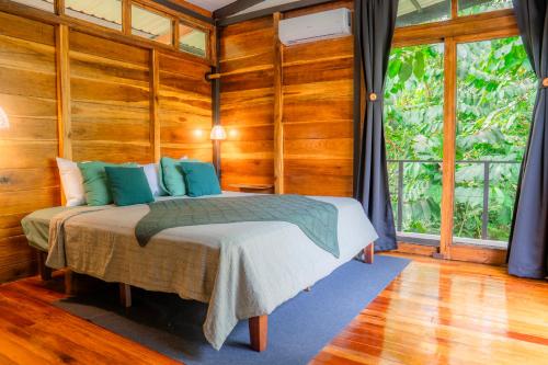 a bedroom with a bed with wooden walls and a window at Arenal Getaway in Fortuna