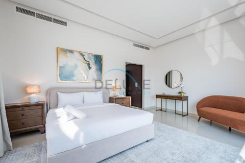 a white bedroom with a bed and a chair at Special Offer with BBQ, Pool Perfect for Groups by Deluxe Holiday Homes in Fujairah