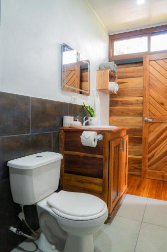 a bathroom with a white toilet and a sink at Arenal Getaway in Fortuna
