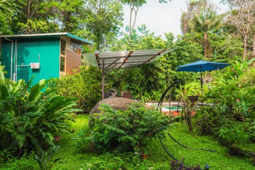 a garden with a green building and an umbrella at Arenal Getaway in Fortuna
