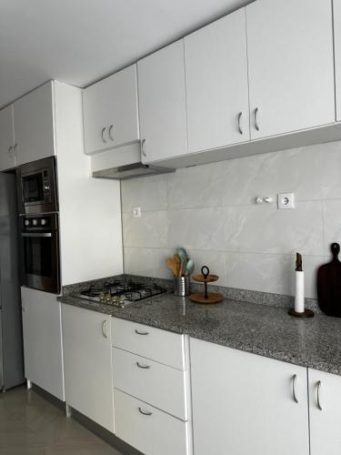 a white kitchen with white cabinets and a stove at T2 Centro cidade in Mindelo