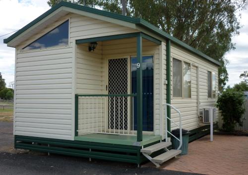 a small white shed with a porch and a staircase at Roma Big Rig Tourist Park in Roma