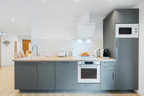 a kitchen with blue cabinets and white appliances at Appartement bord de mer « La Petite Ma-Line » in Cagnes-sur-Mer