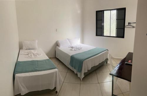 a bedroom with two beds and a window at Pousada Manacá in São José do Rio Pardo